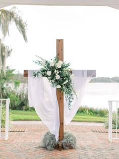 a cross decorated with white flowers and greenery