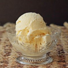 a glass bowl filled with ice cream on top of a woven tablecloth covered place mat