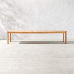 a wooden table sitting on top of a white tiled floor next to a tree branch