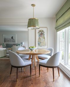 a dining room table surrounded by white chairs