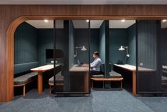 two people sitting at desks in an office setting with privacy screens on the walls