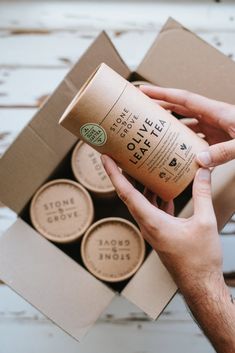 a person holding a coffee cup in front of an open box with four cups inside