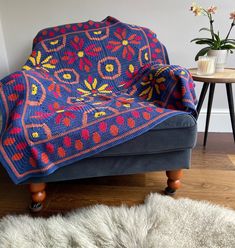 a blue chair with a colorful blanket on it and a rug in front of it