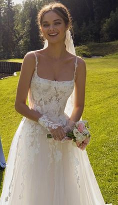 a woman in a wedding dress standing on the grass