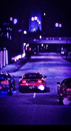 three cars driving down the road at night