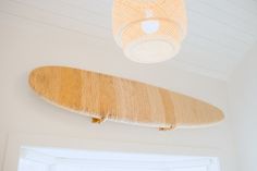 a surfboard hanging from the ceiling in a room with white walls and wood trim