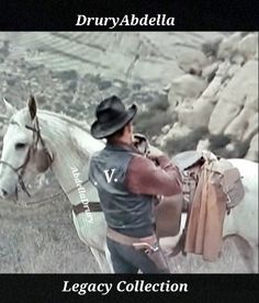 a man riding on the back of a white horse next to a rocky mountain range