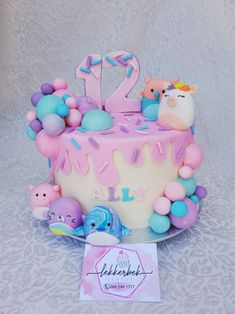 a birthday cake decorated with fondant and pastel decorations, is displayed on a table