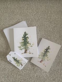 three cards with watercolor trees on them sitting on the ground next to each other