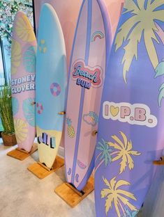 several surfboards are lined up on display in a room with plants and palm trees