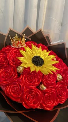 a bouquet of red roses with a sunflower in the middle and a crown on top