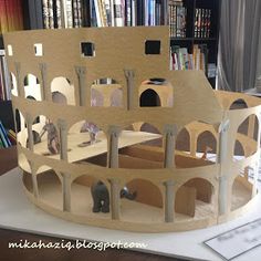 a cardboard model of a castle with an elephant in the center and bookshelves behind it