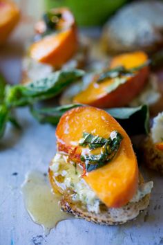 an open face sandwich with peaches and spinach leaves on the side, sitting on a white surface