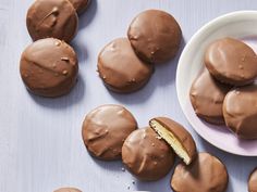 chocolate covered cookies are on a plate next to a bowl