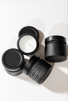 three black containers sitting next to each other on a white surface with one open and the other closed