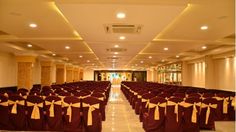 rows of chairs with yellow sashes and bows on them are lined up in an empty hall