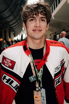 a young man wearing a red, white and black jacket with tags around his neck