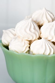 a green bowl filled with whipped cream on top of a table