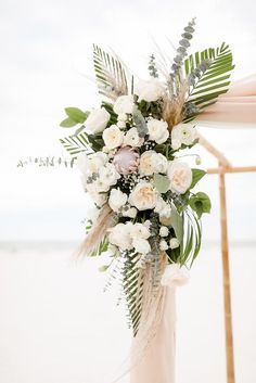 a wedding arch decorated with white flowers and greenery