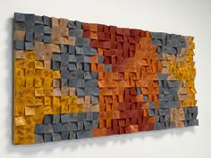 an abstract piece of art made out of wood and oranges, yellows and browns