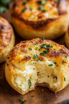 several baked breads with cheese and herbs on a wooden cutting board in the background