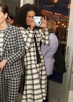 two women standing next to each other taking pictures