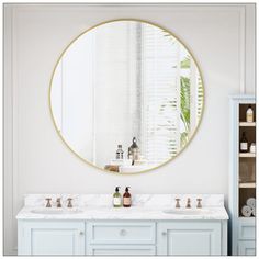 a bathroom with two sinks and a round mirror