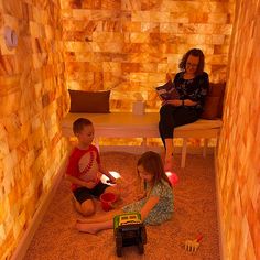 two children are playing with toys in a room that is made out of wood and stone