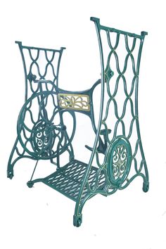 a green metal sewing machine stand with wheels on it's sides and an intricately designed design