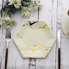 a white plate topped with a piece of cake on top of a wooden table next to a knife and fork