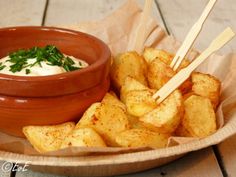 a bowl filled with fries and dip on top of a wooden table