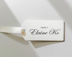 a table name tag attached to a wall with a white ribbon on it's end