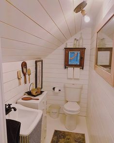 a bathroom with a toilet, sink and mirror in it's attic style home