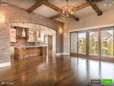 a large open floor plan with wood floors and exposed brick walls, an arched doorway leading to the kitchen