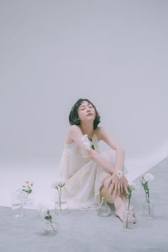 a woman sitting on the ground with flowers in front of her