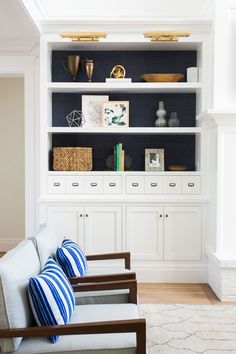 a living room filled with lots of furniture and bookshelves on top of white shelves