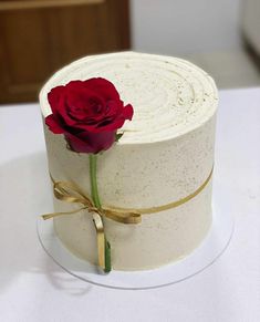 a white cake with a single red rose on top