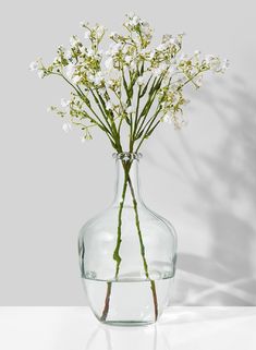 a clear vase filled with white flowers on top of a table