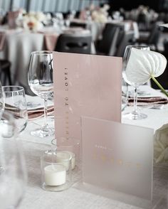 the table is set with wine glasses, candles and cards for guests to write on