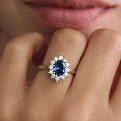 a close up of a person's hand with a ring on it and a blue stone in the middle