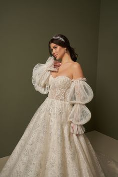 a woman in a white wedding dress posing for the camera with her hand on her face