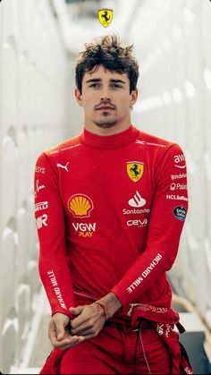 a man in a red suit sitting down with his hands on his hips and looking at the camera