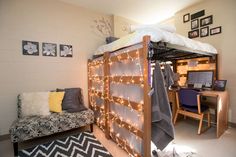 a loft bed with lights on it and a desk in the corner next to it