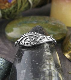 Material: 100% Sterling silver Weight: 1.9 grams Front of ring is 1/4 inch tall (6mm) Band in back is 1/16 inch wide (1.5mm) Item number: wh284 Several nice details make this a very decorative Evil Eye ring. The almond-shaped outline of the eye is created by a simple line that loops upon itself on either side, almost like an infinity symbol or a Celtic knot. In contrast, the 'eyelashes' are just six short vertical lines above that give the eye a slightly Egyptian look, and the bottom of the eye Silver Symbolic Toe Rings, Silver Symbolic Stackable Rings, Symbolic Silver Stackable Rings, Finding Feathers, Moon Pentacle, Angel Ring, Pentagram Pendant, Hummingbird Pendant, Sweet Necklace