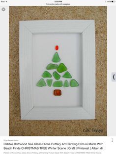 a white frame with a green and red christmas tree made out of sea glass on the inside