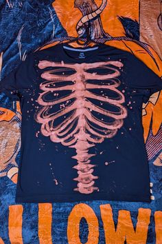 a t - shirt with a skeleton on it is laying on a colorful cloth covered bed