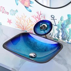 a bathroom sink that has a blue glass bowl on the top and an ocean themed mirror above it