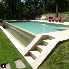 an empty swimming pool in the middle of a grassy area with stairs leading up to it