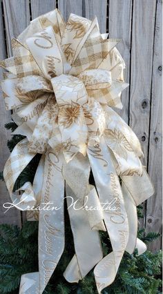 a christmas tree bow hanging on the side of a wooden fence