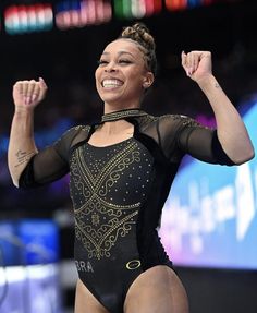 a woman in a black leotard and gold bodysuit is raising her fist